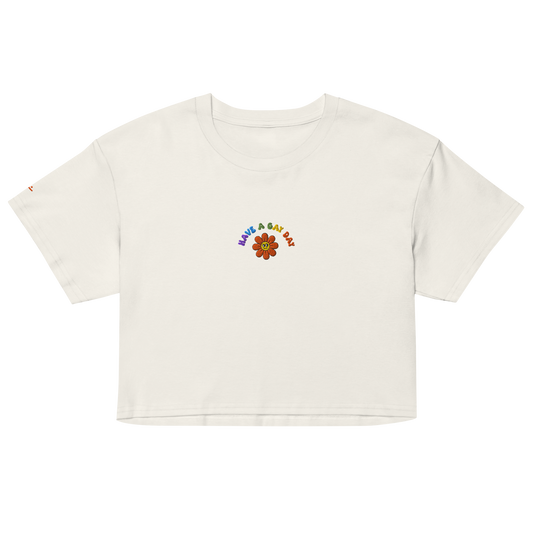 Off-White crop top, front view – small colorful"have a gay day" and flower with friendly face embroidery on chest
